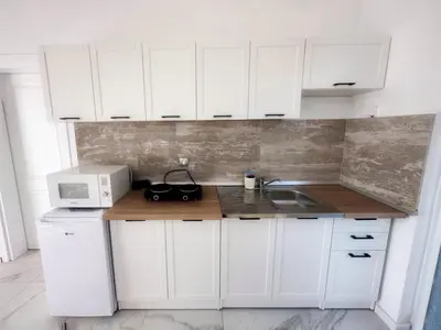 a white kitchen with a sink and a microwave at Almond Apartments in Sveti Stefan