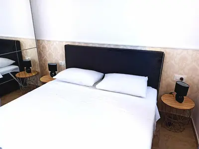 a bedroom with a bed with two pillows and two tables at Almond Apartments in Sveti Stefan