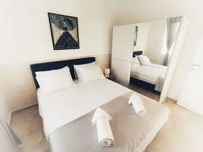 a bedroom with a large white bed and a mirror at Almond Apartments in Sveti Stefan
