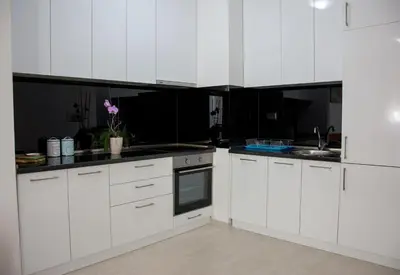 a white kitchen with black counters and white cabinets at Apartments Milica in Becici