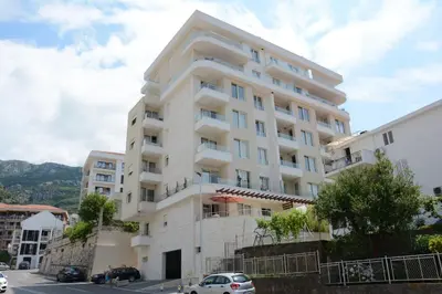 a white building with cars parked in front of it at Apartments Milica in Becici