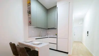 a kitchen with white cabinets and a table and chairs at DiVa Lux Apartment in Soho City complex in Bar