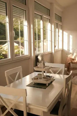 a white table and chairs in a room with windows at Ivana in Rijeka Crnojevića