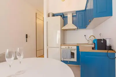 a kitchen with blue cabinets and two wine glasses at Delightful Studio Soho City in Bar