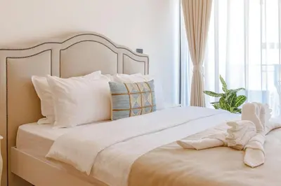 a bed with white sheets and pillows next to a window at Delightful Studio Soho City in Bar