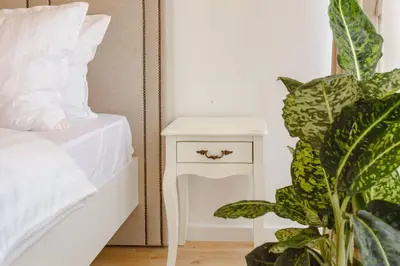 a white night stand next to a bed with a plant at Delightful Studio Soho City in Bar