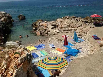 a beach with umbrellas and people in the water at MonoLiza in Utjeha