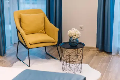 a yellow chair and a table with a vase of flowers at Atelier in Ulcinj