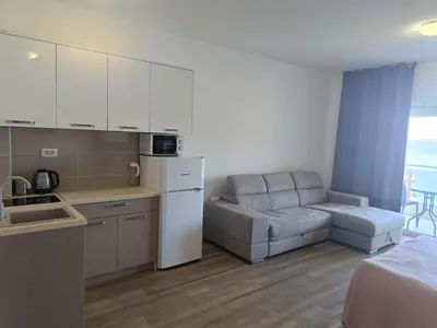 a kitchen and a living room with a couch at Apartments GC 3 in Rafailovici