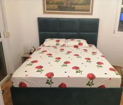 a bedroom with a bed with red flowers on it at Sveti Stefan- Apartment Dora in Sveti Stefan