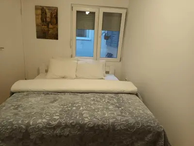 a bed in a small room with two windows at Sveti Stefan- Apartment Dora in Sveti Stefan