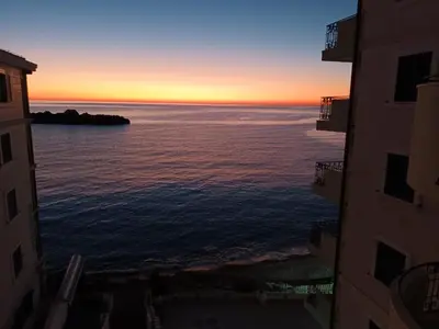 a sunset over the ocean between two buildings at Sveti Stefan- Apartment Dora in Sveti Stefan