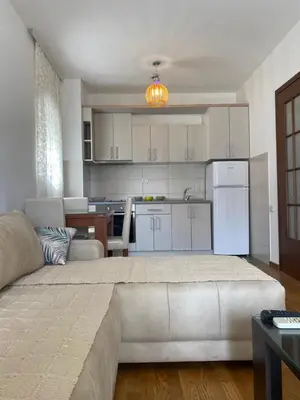 a kitchen and a living room with a large couch at Apartment Vesna City PG in Podgorica