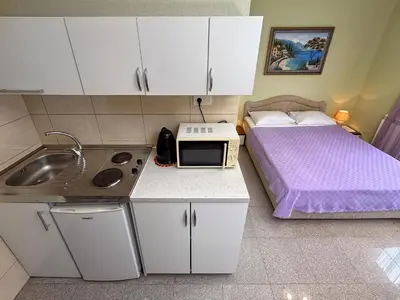 a small kitchen with a bed and a microwave at VILA TARA in Sutomore