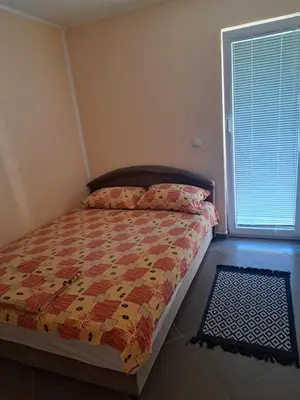 a bedroom with a bed with a comforter and a window at MD APARTMANI CANJ in Čanj