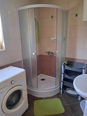 a shower in a bathroom with a washing machine at MD APARTMANI CANJ in Čanj