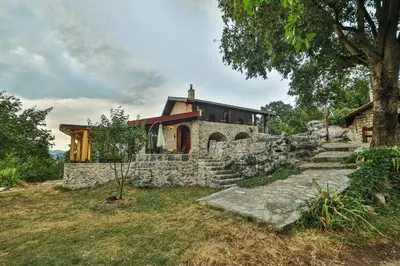 a stone house with a tree and stairs in front of it at Royal Villa Ana in Cetinje