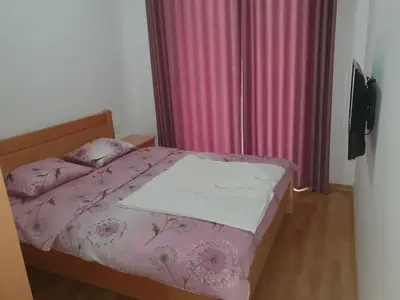 a bedroom with a bed with a pink comforter and pillows at Apartman Krstajić in Budva