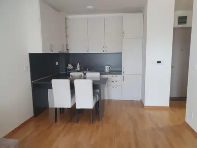 a kitchen with white cabinets and a table with white chairs at Apartman Krstajić in Budva