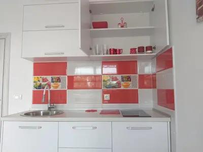 a kitchen with white cabinets and red tiles at Helena Apartment in Ulcinj