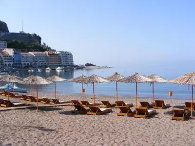 a group of chairs and umbrellas on a beach at Adriatic apartman in Becici
