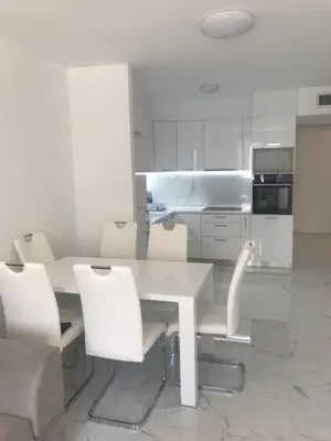 a kitchen with a white table and white chairs at Adriatic apartman in Becici