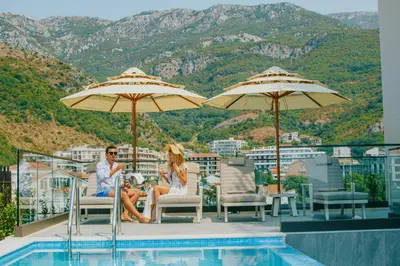 a man and woman sitting under umbrellas next to a pool at Katamare Hotel in Budva