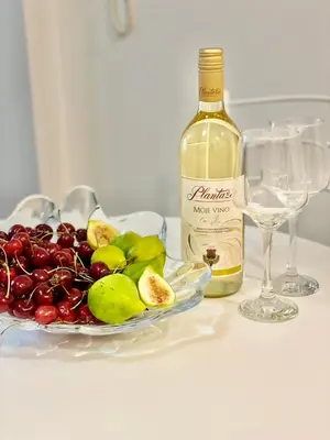a bottle of wine and a bowl of fruit on a table at Olive Square Apartment Budva in Budva