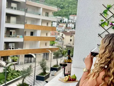 a woman drinking a glass of wine on a balcony at Olive Square Apartment Budva in Budva
