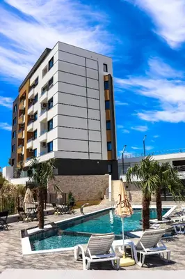 a hotel with a swimming pool with chairs and a building at Eagles Apartments & Suites in Ulcinj