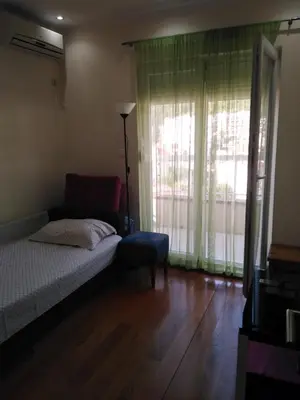 a bedroom with a bed and a chair and a window at Stan Budva Apartman in Budva