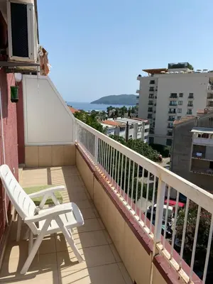a balcony with a chair and a view of a city at Stan Budva Apartman in Budva