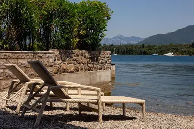 two chairs and a bench next to a body of water at Aquamarine House in Tivat