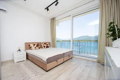 a bedroom with a bed and a large window at Aquamarine House in Tivat