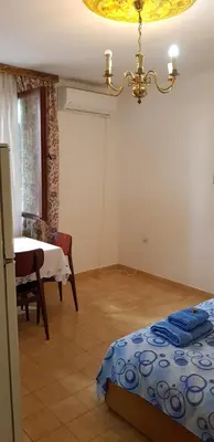 a bedroom with a bed and a table and a chandelier at Apartman Veliki Pijesak in Dobra Voda