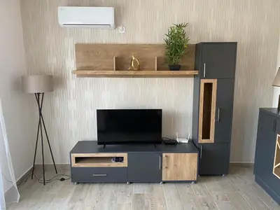 a living room with a flat screen tv on a entertainment center at Viola Apartmanházak Family Apartman in Donji Susanj