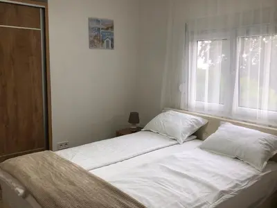 a bed with white sheets and pillows in a bedroom at Viola Apartmanházak Family Apartman in Donji Susanj