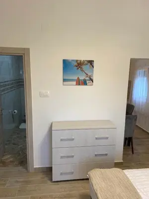 a bedroom with a dresser and a picture on the wall at Viola Apartmanházak Family Apartman in Donji Susanj