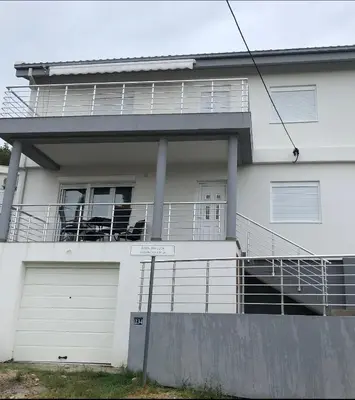 a white house with a balcony and a garage at Viola Apartmanházak Family Apartman in Donji Susanj