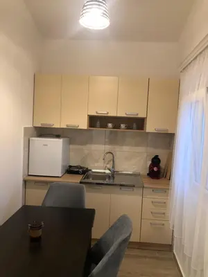 a kitchen with white cabinets and a table and a sink at Viola Apartmanházak Family Apartman in Donji Susanj