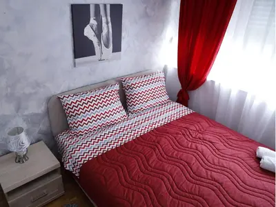 a bedroom with a bed with a red blanket and a window at Apartment Mona in Podgorica