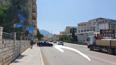 a man walking down a city street with a car at Candy apartment central location Bečići in Becici