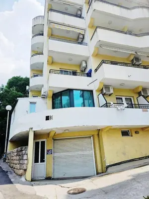 a tall yellow building with a garage at Candy apartment central location Bečići in Becici