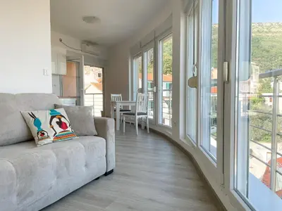 a living room with a couch and large windows at UpART House in Petrovac na Moru