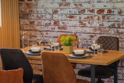 a wooden table with chairs and a brick wall at Stylish Two Bedroom Apartment at Ljubovic-Hill Park in Podgorica