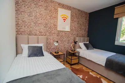 a bedroom with two beds and a brick wall at Stylish Two Bedroom Apartment at Ljubovic-Hill Park in Podgorica