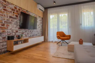 a living room with a brick wall and a tv at Stylish Two Bedroom Apartment at Ljubovic-Hill Park in Podgorica