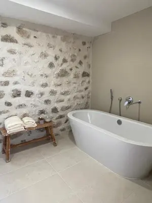 a white bath tub in a bathroom with a stone wall at Villa Portico in Budva