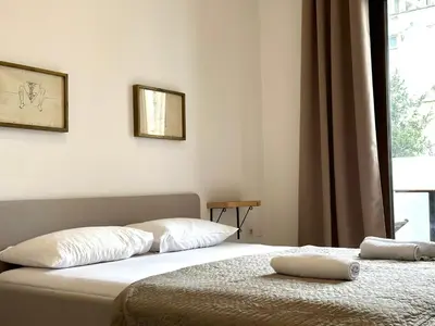 a bedroom with two beds and a window at Guest house Kamelija in Budva