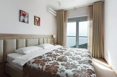 a bedroom with a bed and a large window at Top-hill stunning view 2 bdr apt with swimming pool in Komoševina